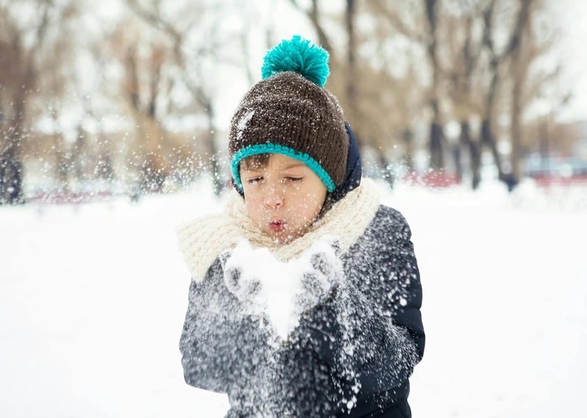 Enfant qui souffle sur de la neige