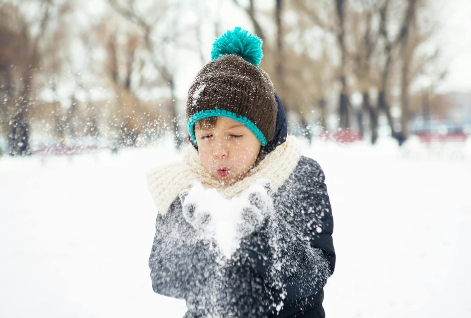 Enfant qui souffle sur de la neige